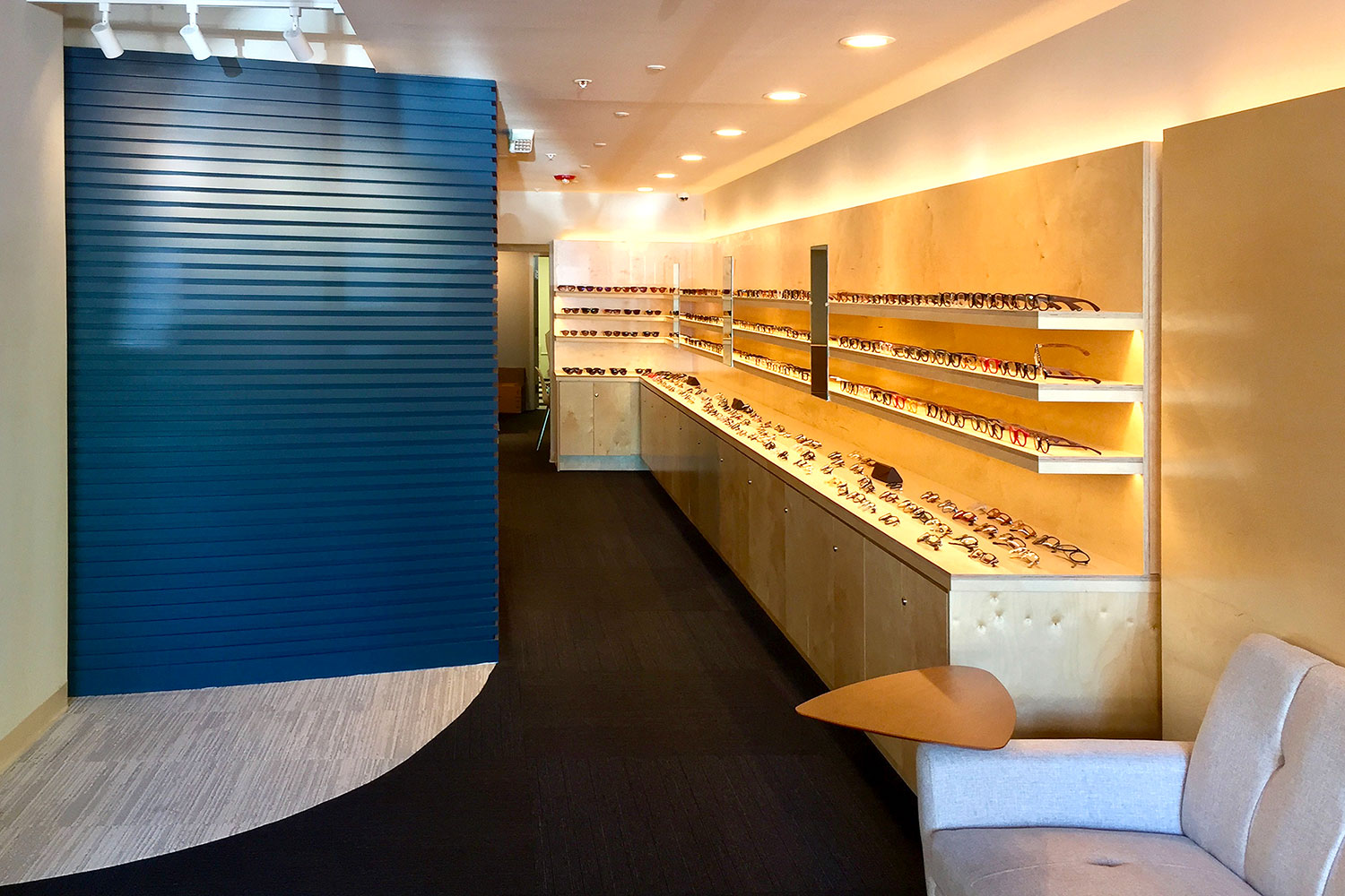 Store selling eyeglasses in Hayes Valley. Interior view. Lighted display racks and countertops with merchandise.